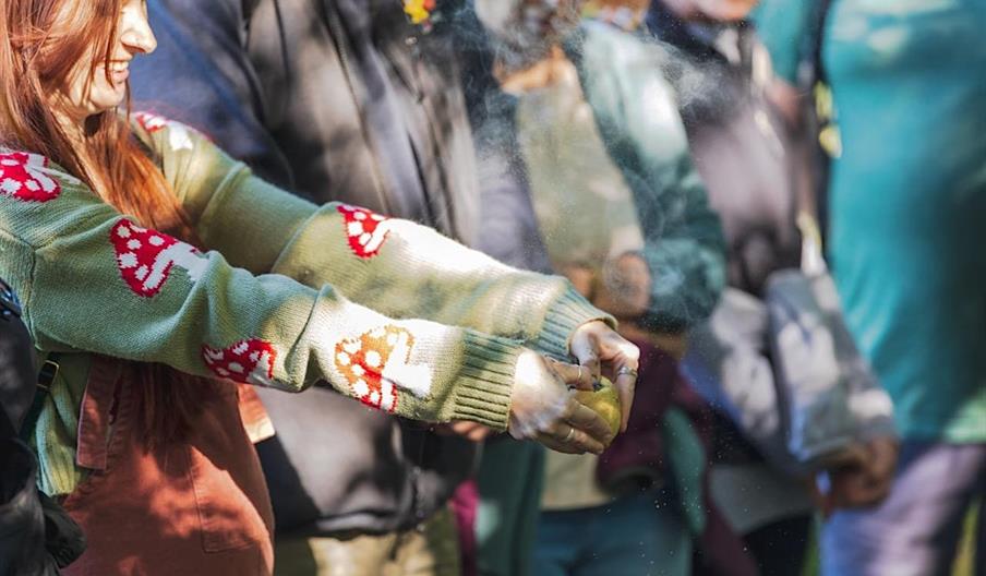 A group of people looking at a girl who is squeezing a fruit