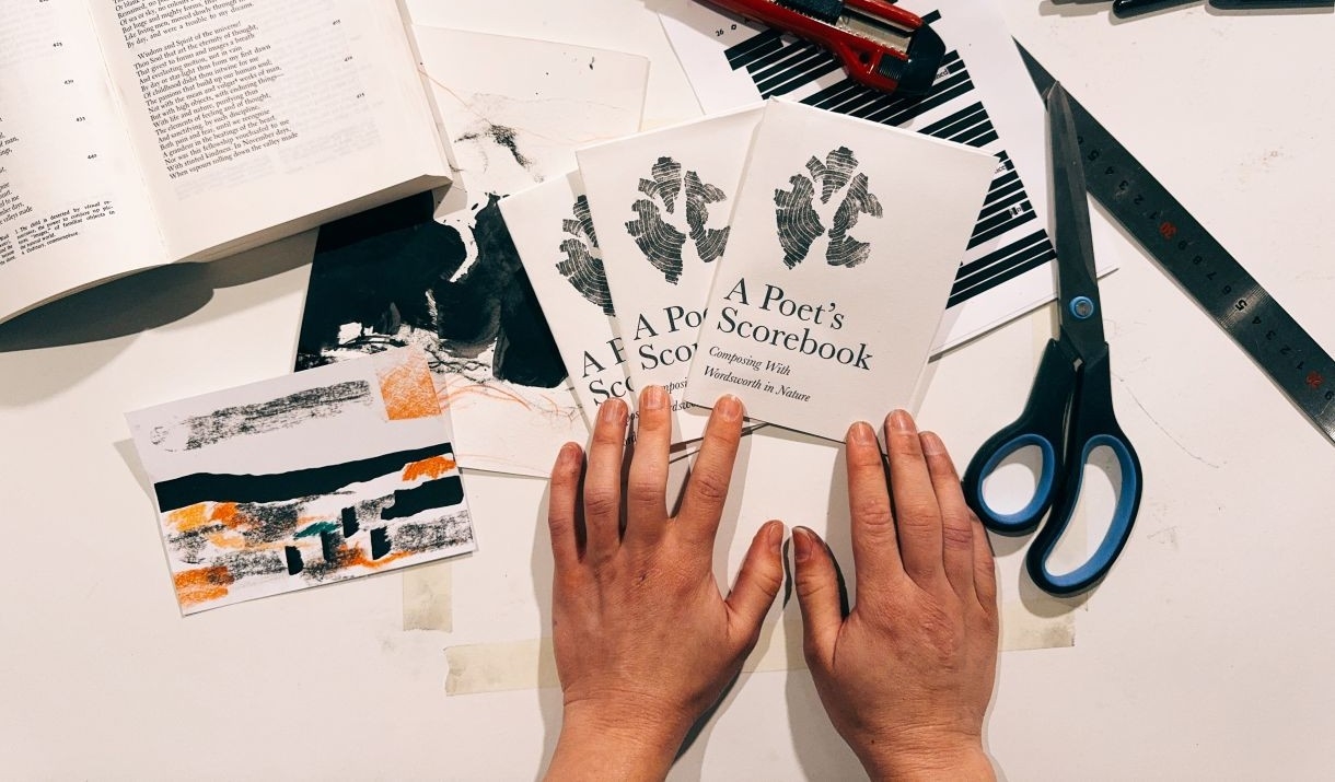 Hands holding copies of a booklet titled 'A Poet’s Scorebook: Composing With Wordsworth in Nature,'