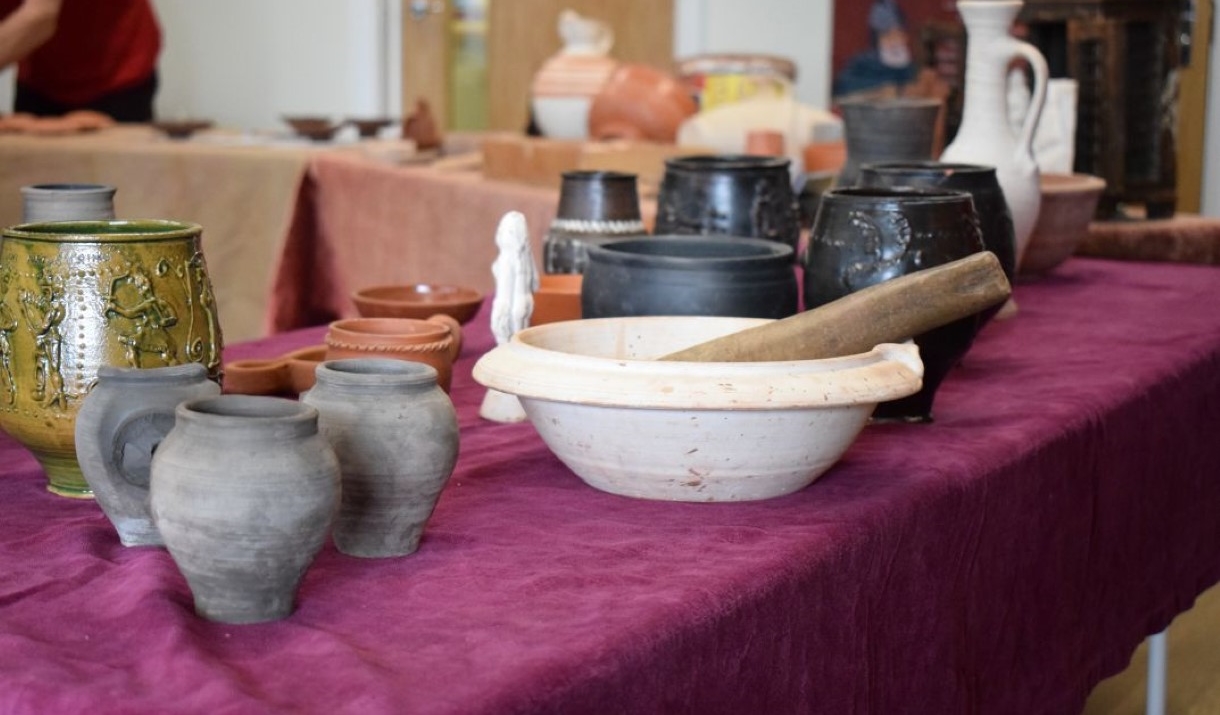 Image of a selection of Roman pottery replicas on a purple tabelcoth.
