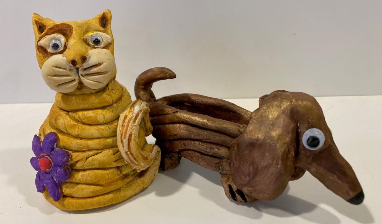 A rustic cat and dog made of painted clay.