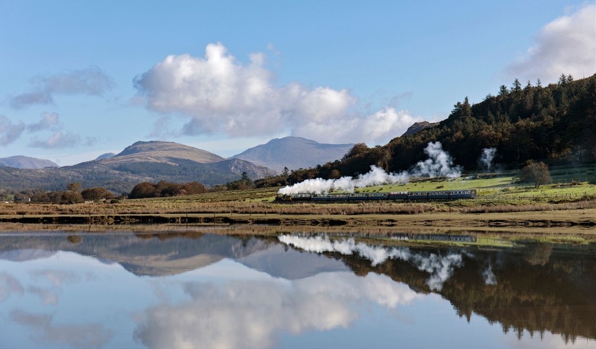 Ravenglass and Eskdale Railway Train with a scenic mountain backdrop and lake reflection © Mark Fielding