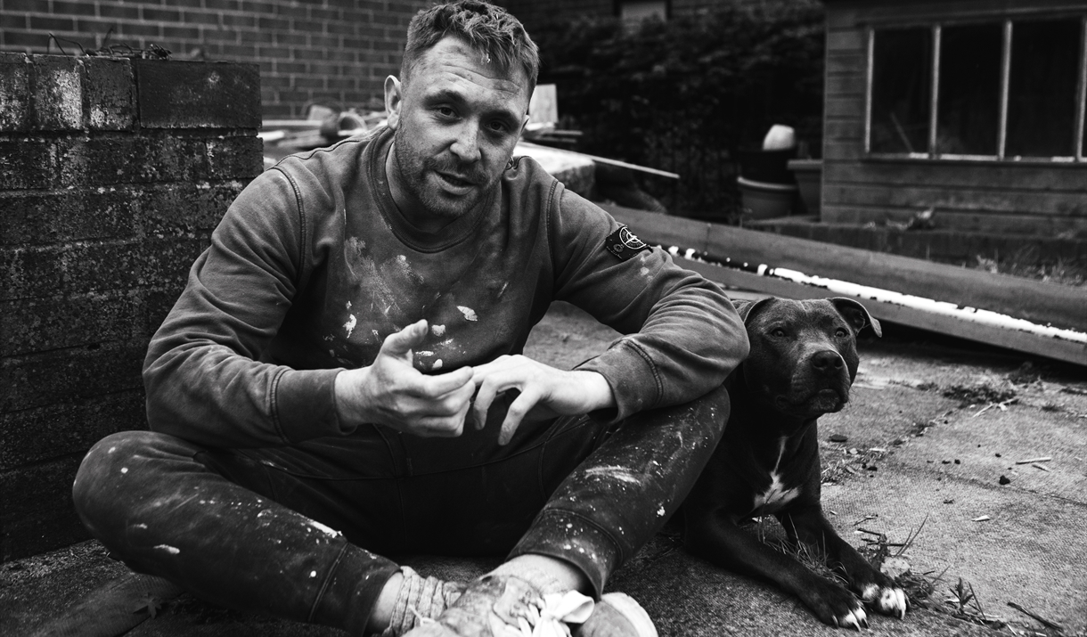 Black and white image of character, Danny, sat with a pit bull dog.