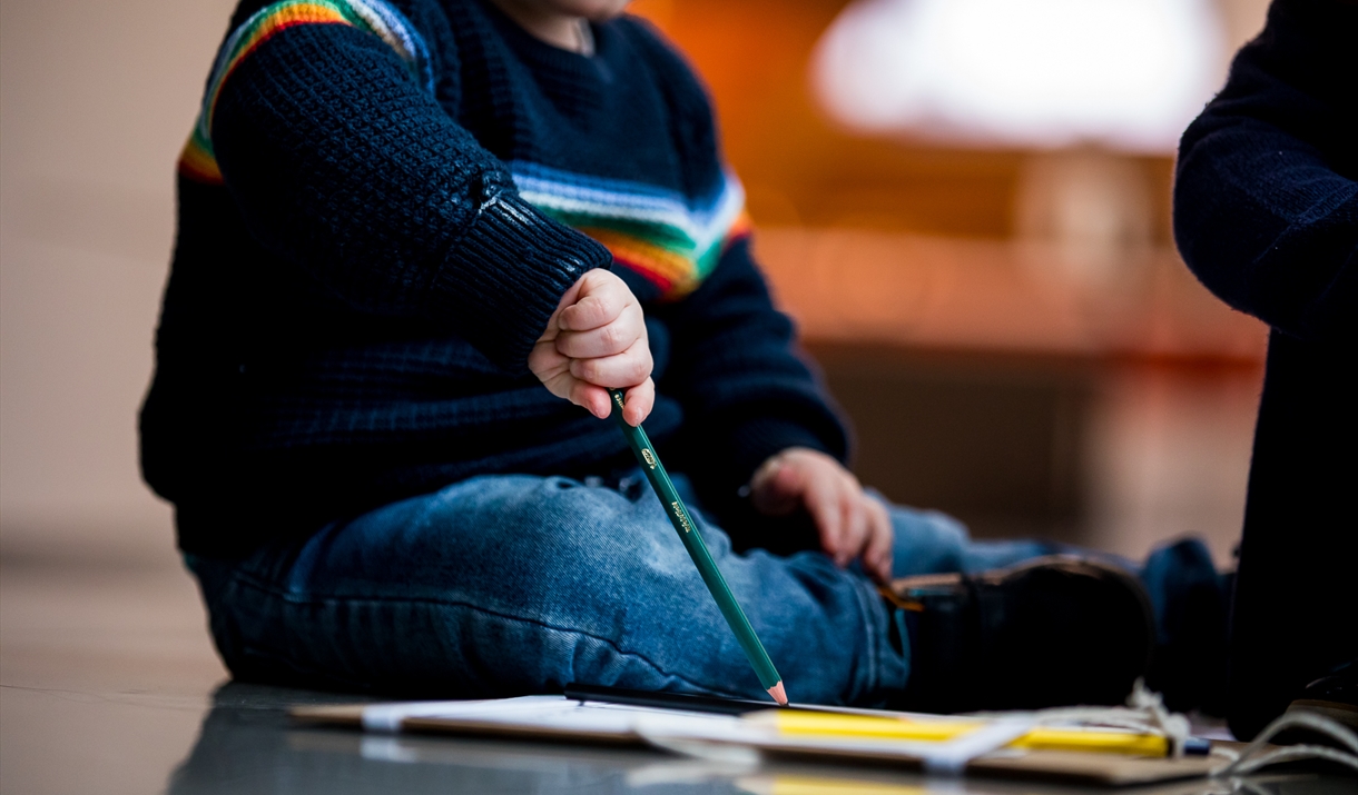 A child drawing on some paper sat on the floor