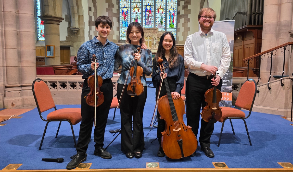 Agogo String Quartet stood for a photo in church with their instruments