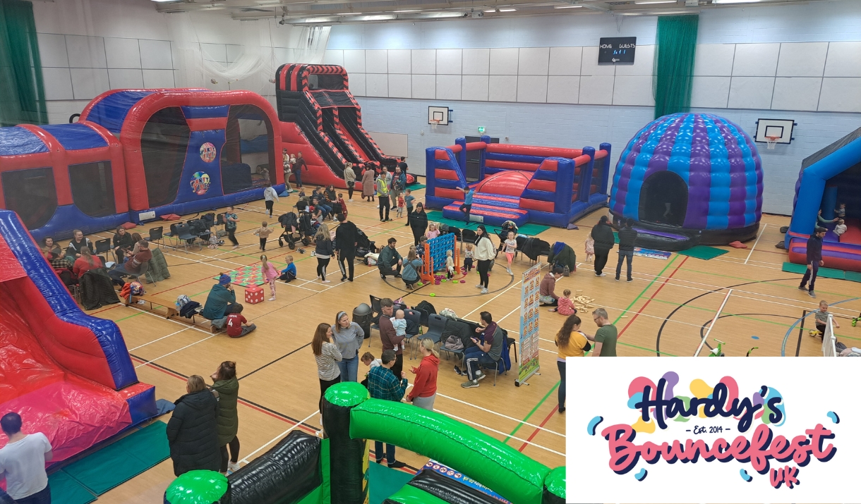 Indoor family fun event with large inflatable obstacle courses, bouncy castles, slides, and activity areas. Children and parents are playing, while ot