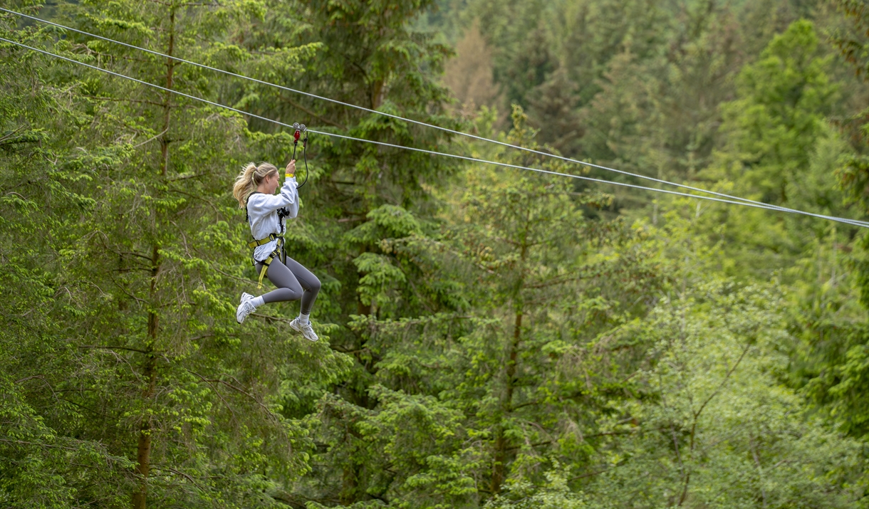 Women zip lining through Whinlatter Forest