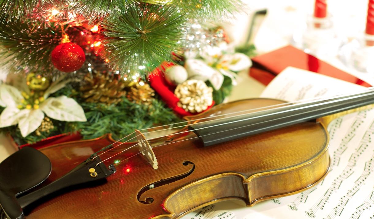 Violin placed face up next to a Christmas tree