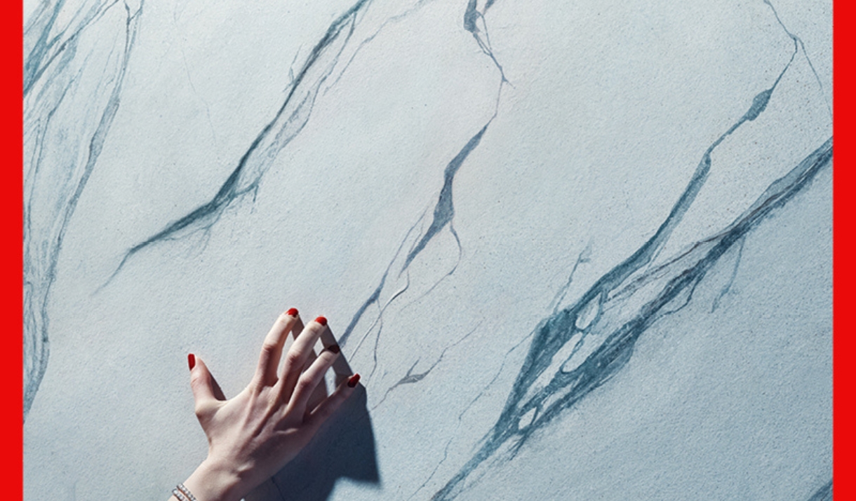 hand with red nail polish brushing against a marble wall