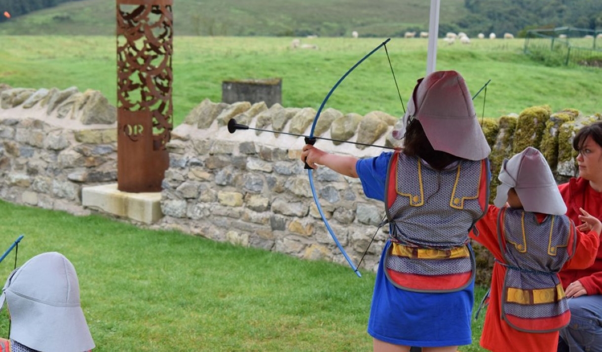Image of a person dressed up as a Roman soldier practicing archery.