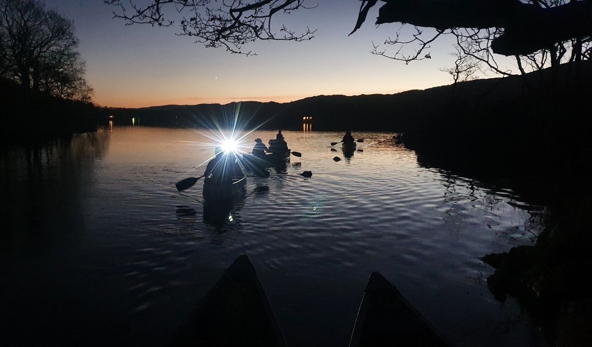 People night time canoeing under stars with a headtorch beam