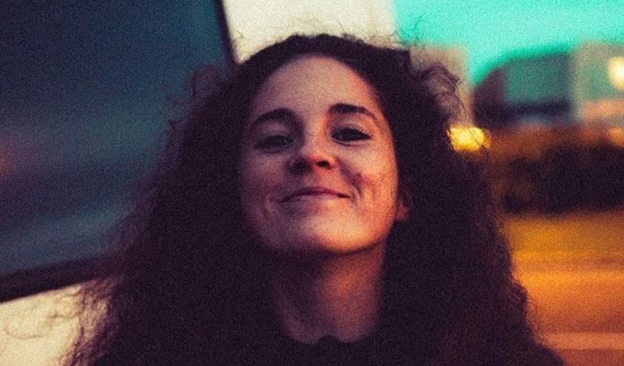 person smiling at camera holding a flower