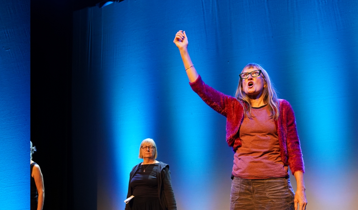 A person on a stage holding their right arm in the air