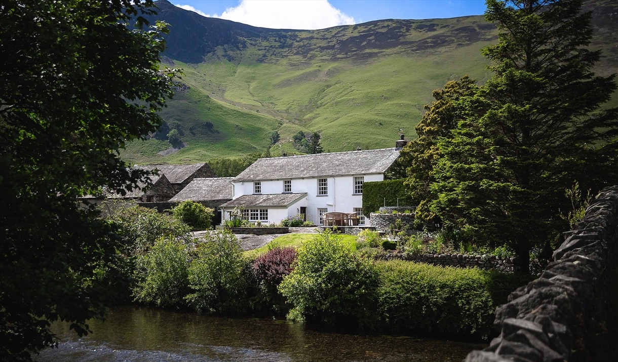 Exterior view from over the river of Grange Bridge Cottage in Borrowdale, Lake District