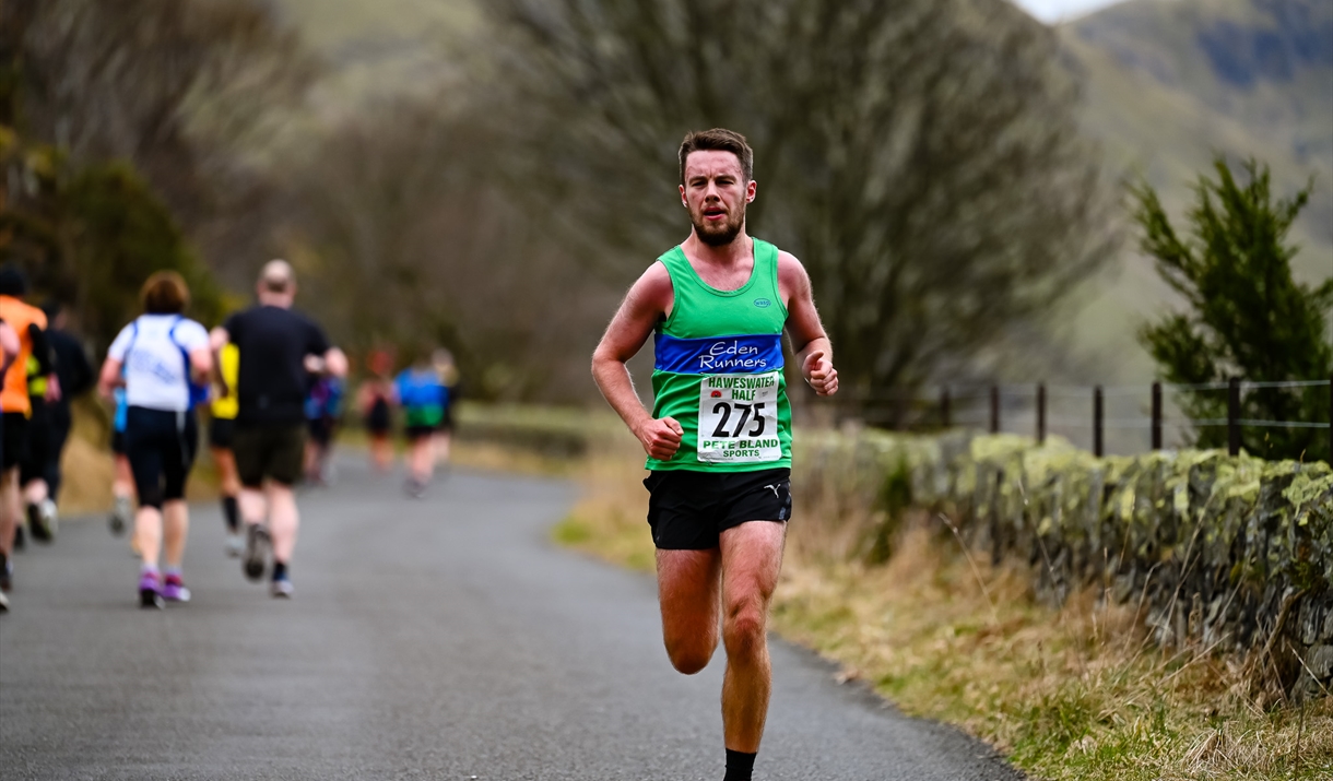 A man running along a rural road with a backdrop of mountains