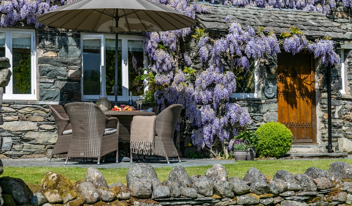 Exterior of Stone Cottage in Patterdale, Lake District with Wisteria and outdoor patio seating