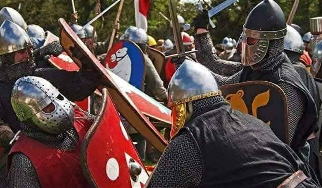 Medieval reenactment battle, two armies fighting each other with swords and shields.