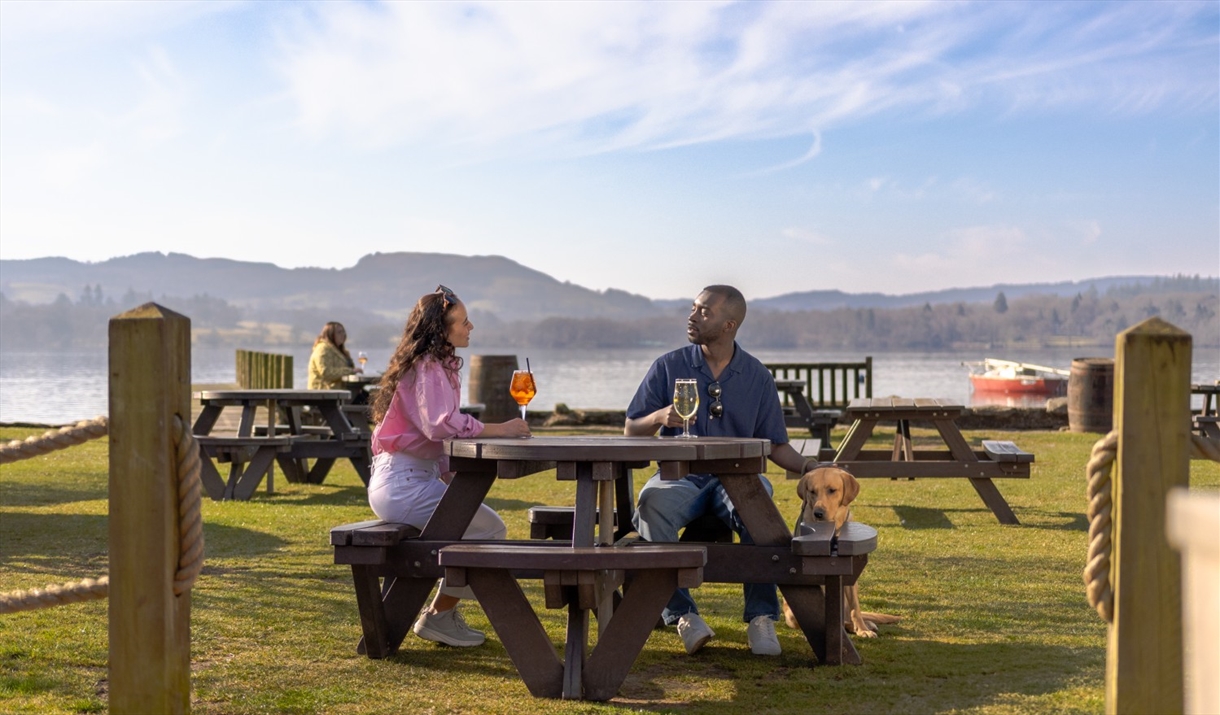 Guests sitting outside with drinks and a dog at The Wateredge Inn in Ambleside, Lake District