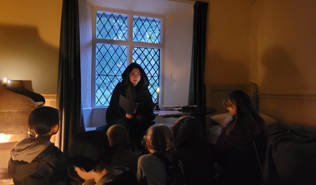 Young woman in historical clothing reading stories by candlelight