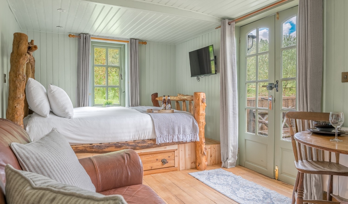 Interior of Juniper Lodge, with double bed, couch, and dining setup at Coniston Shepherd Hut Lodges in Coniston, Lake District