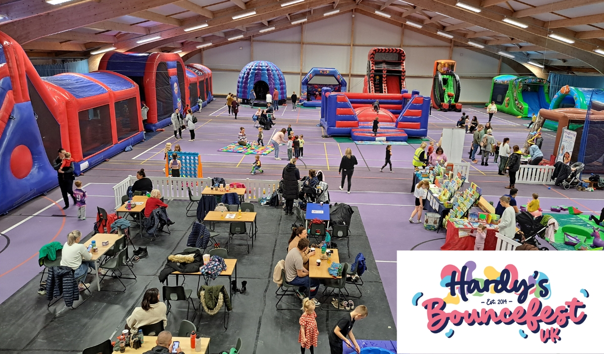 Indoor family fun event with large inflatable obstacle courses, bouncy castles, slides, and activity areas. Children and parents are playing, while ot