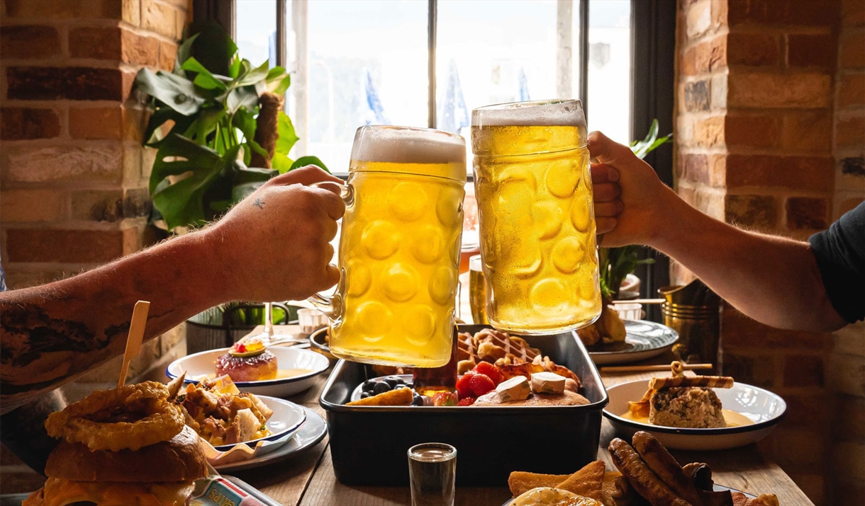 Visitors Toasting Beers over a Table with Food at Lake View Garden Bar in Bowness-on-Windermere, Lake District