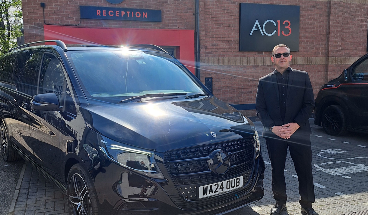 Driver guide from Lakeland Chauffeurs poses with a Mercedes luxury coach