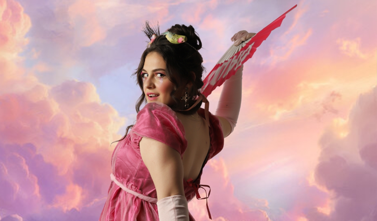 A still from the play Clementine featuring Clementine fanning herself with a backdrop of clouds
