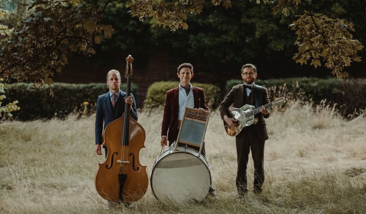 Photo of "Leeds City Stompers" standing in a field with their respective instruments
