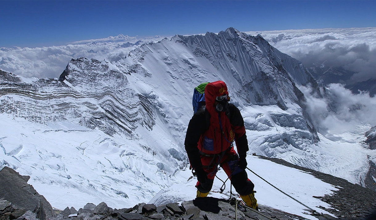 Keith Partridge climbing a snowy mountaintop above the clouds