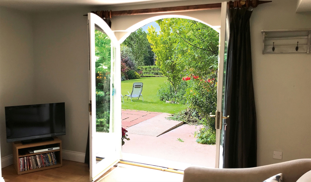 Double doors leading to the garden and outdoor seating at The Cottage at Linden Farm House in Langwathby, Cumbria