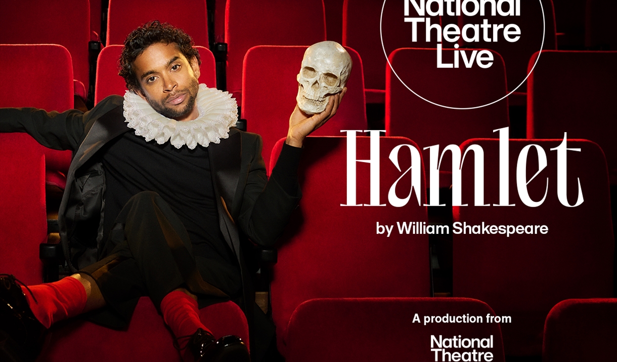 Actor Hiran Abeysekera sat in a theatre seat holding a human skull in his hand recreating a Hamlet scene