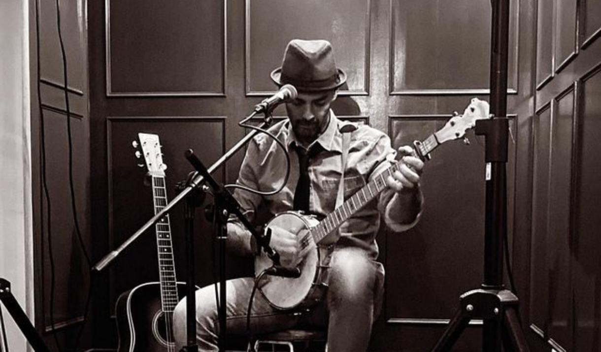 person playing guitar whilst sitting on a chair