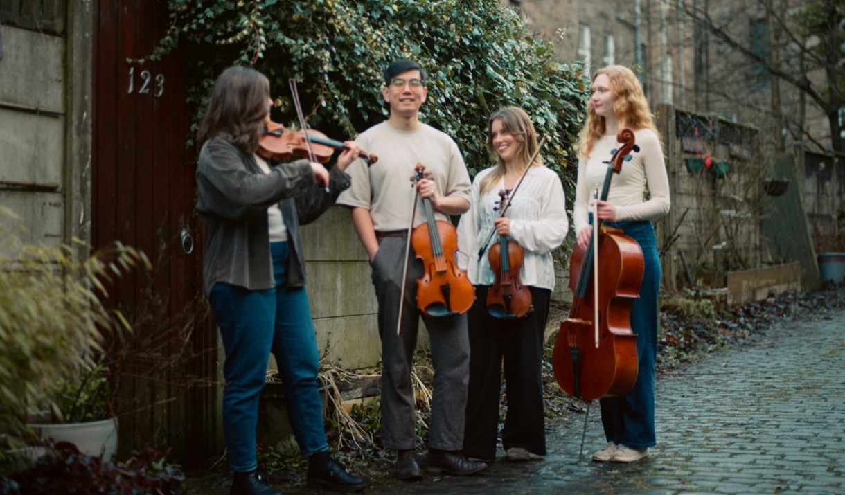 Resol String Quartet standing in an autumnal alleyway with their instruments