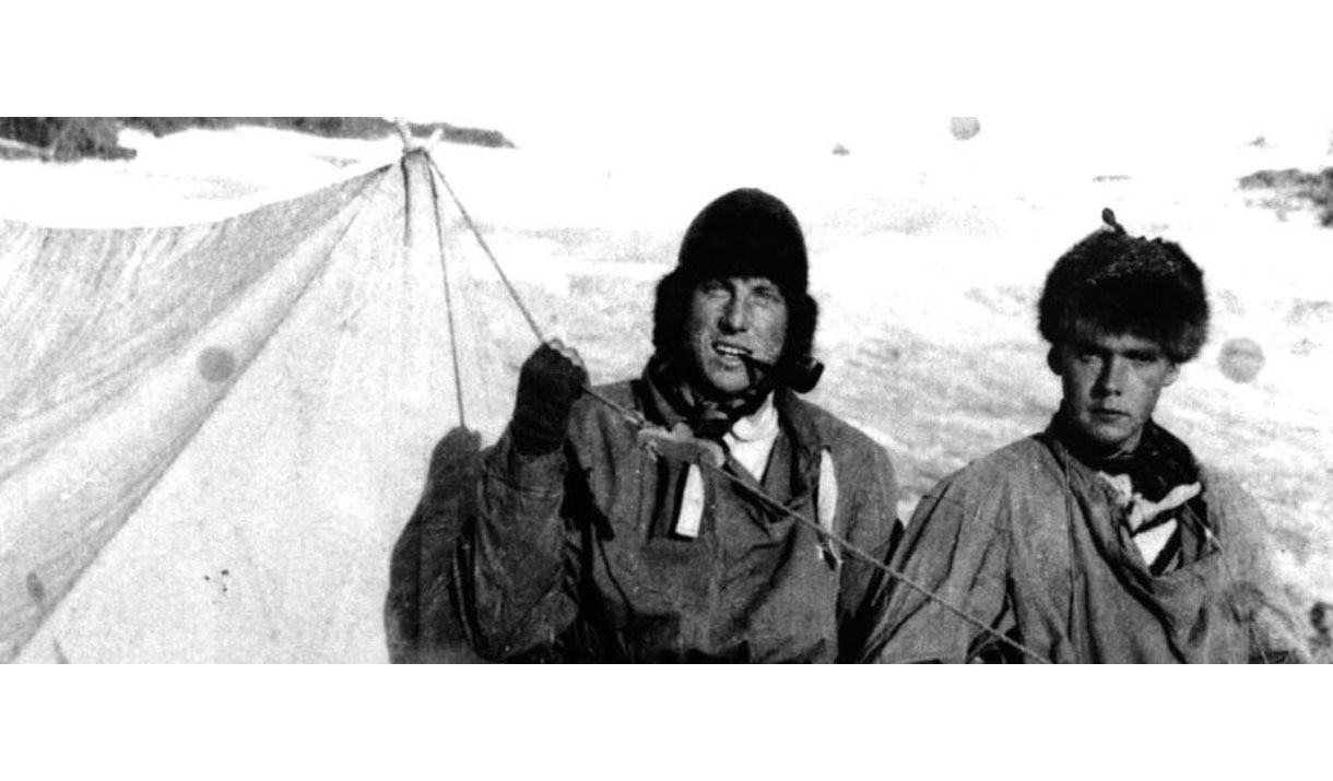 Black and white photo of Sandy Irvine and another mountaineer at a mountain campsite in the snow