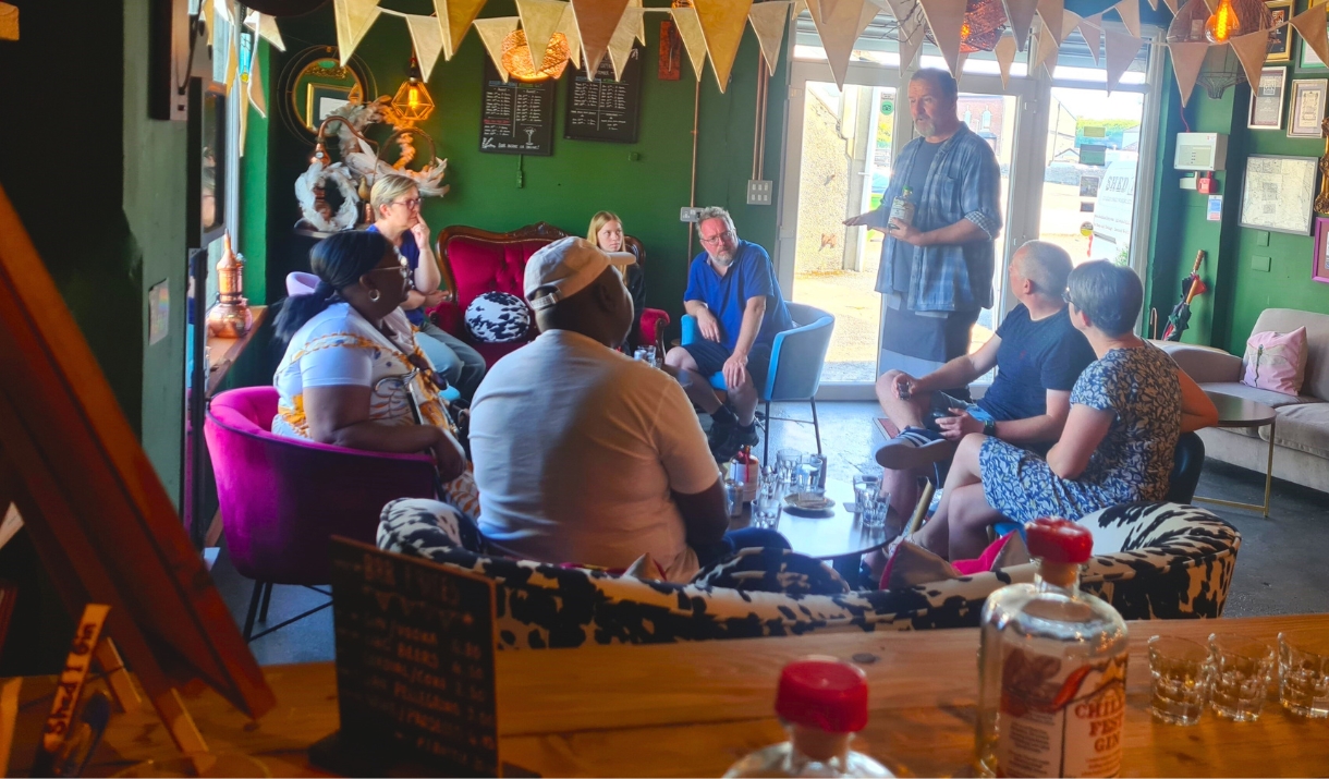 A man giving a talk to a group of people sat down on chairs