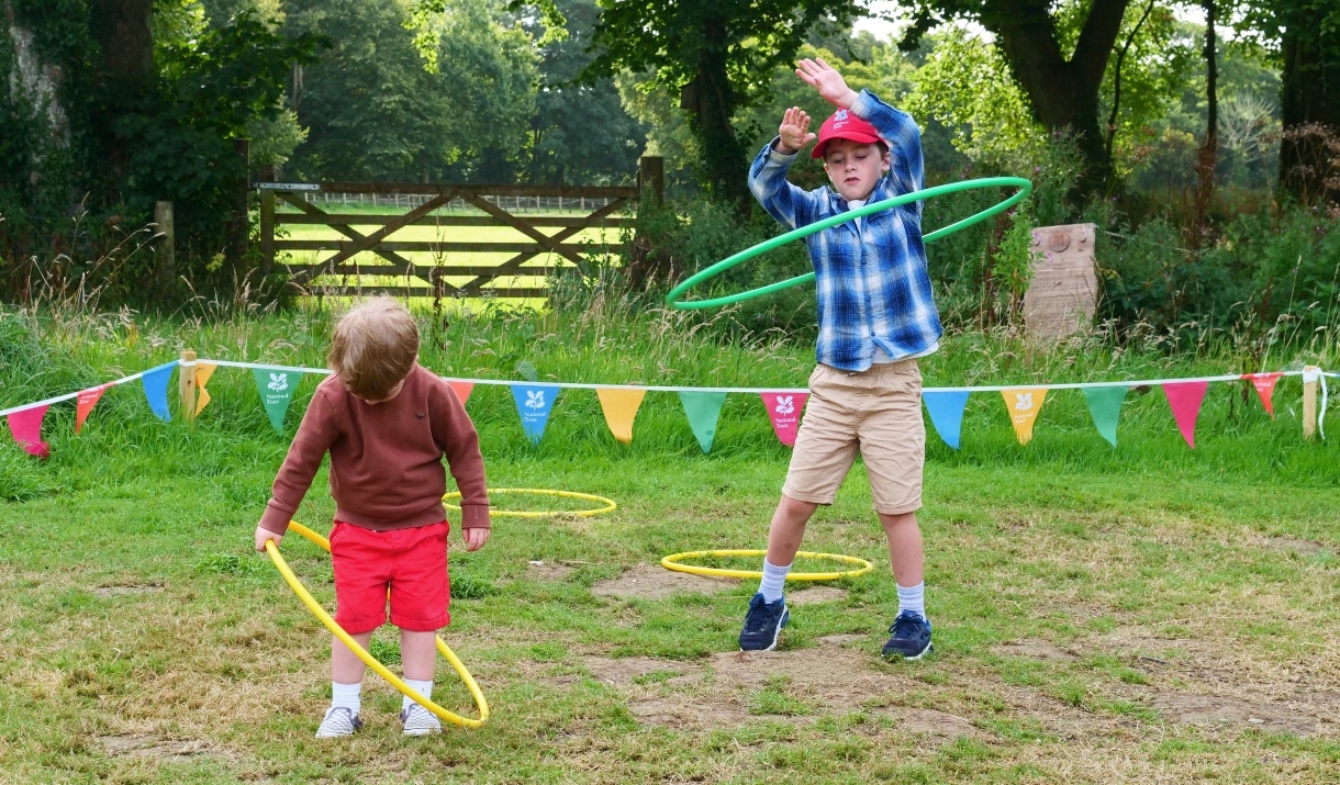 Two children play with hoops in a grassy field