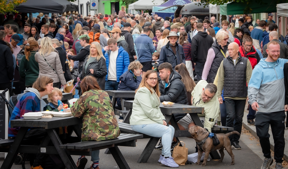 The street is packed with people shopping, eating and drinking