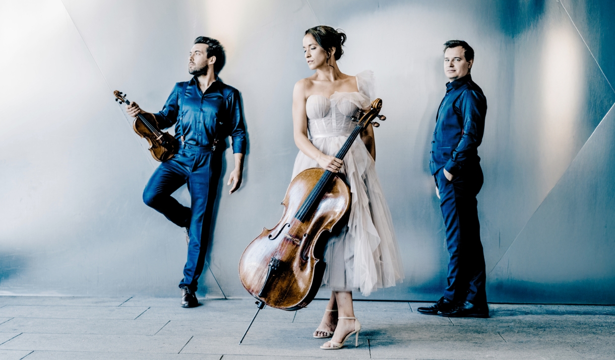 Trio Bohémo stood in a white and blue studio set with their instruments