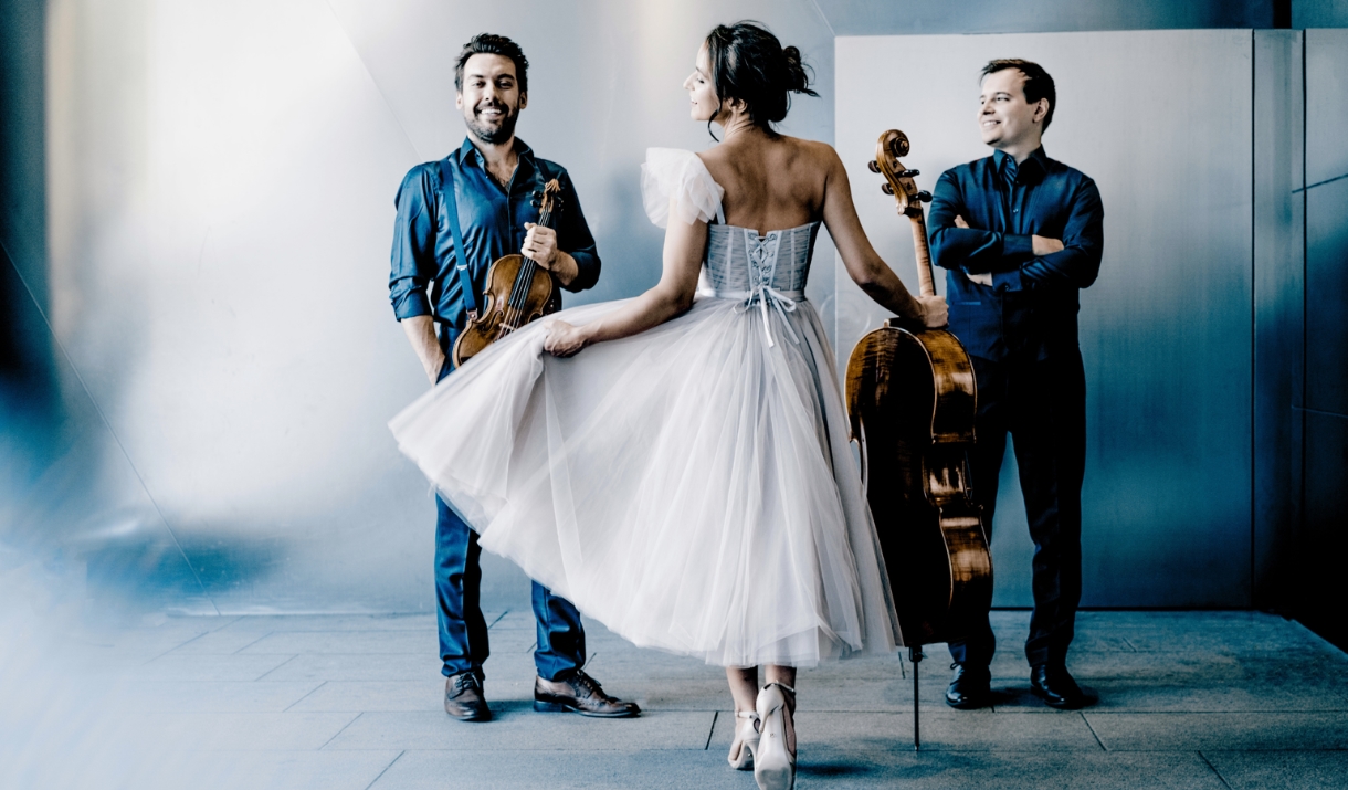 Trio Bohémo stood in a white and blue studio set with their instruments