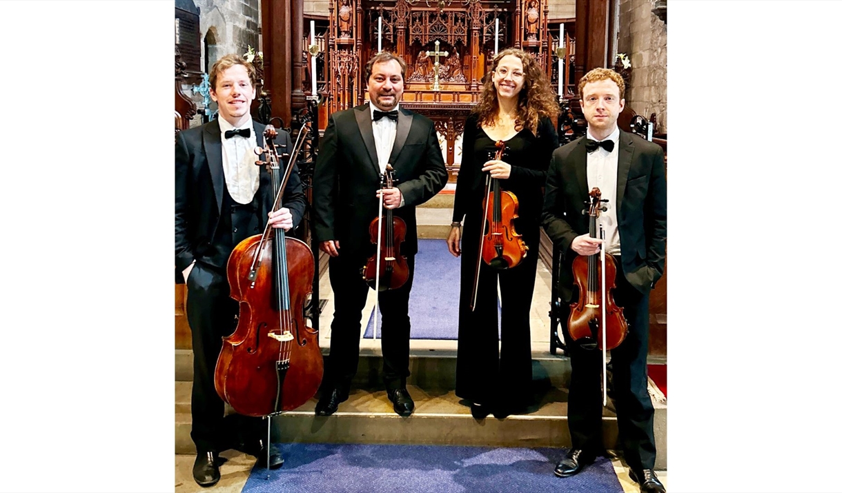 The Northern String Quartet stood in a church with their respective instruments