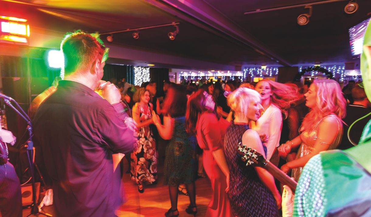 A singer and guitarist performing to a crowd of dancing people