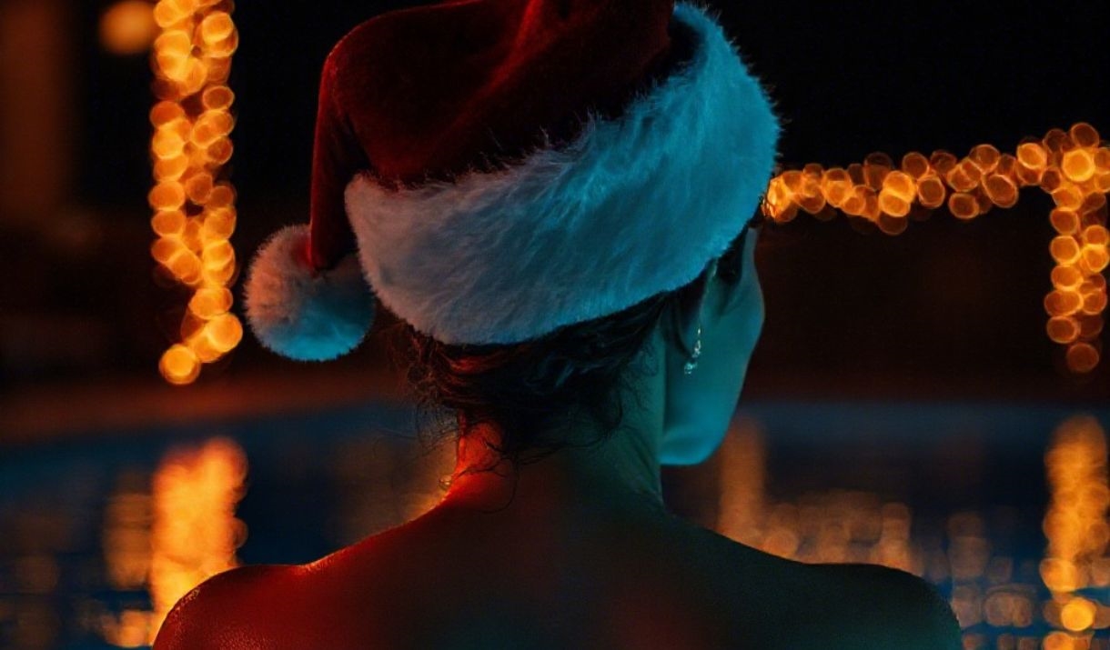 Woman swimming in pool with Santa hat on
