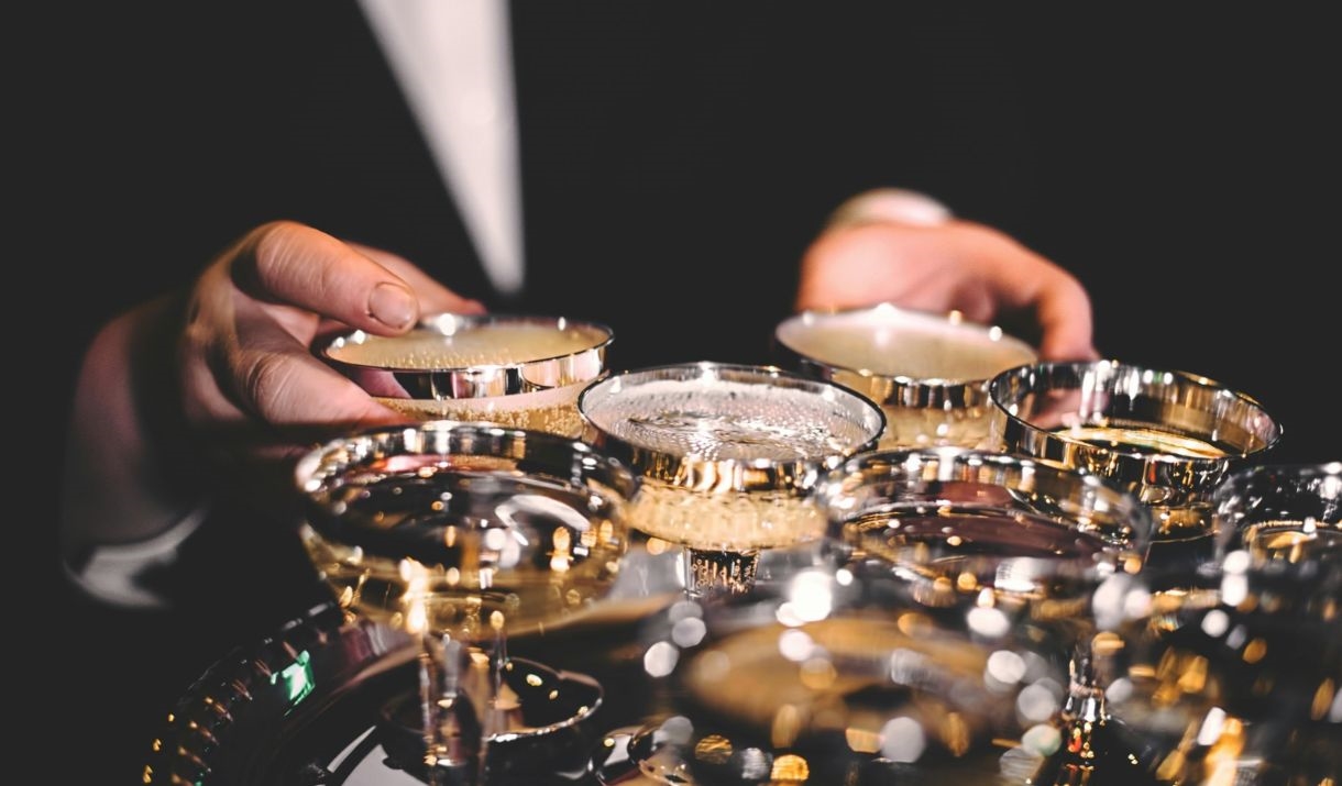 Person wearing a suit holding a tray of luxury champagne