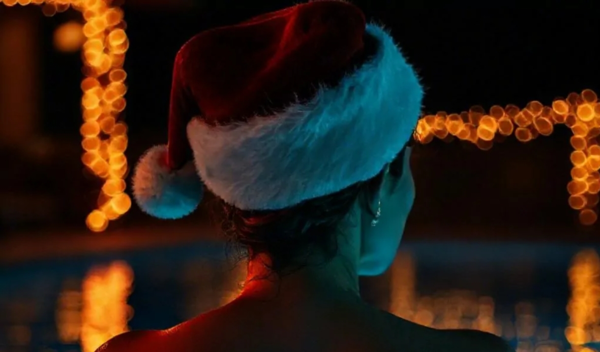 Women wearing a santa hat looking out over a lake at night