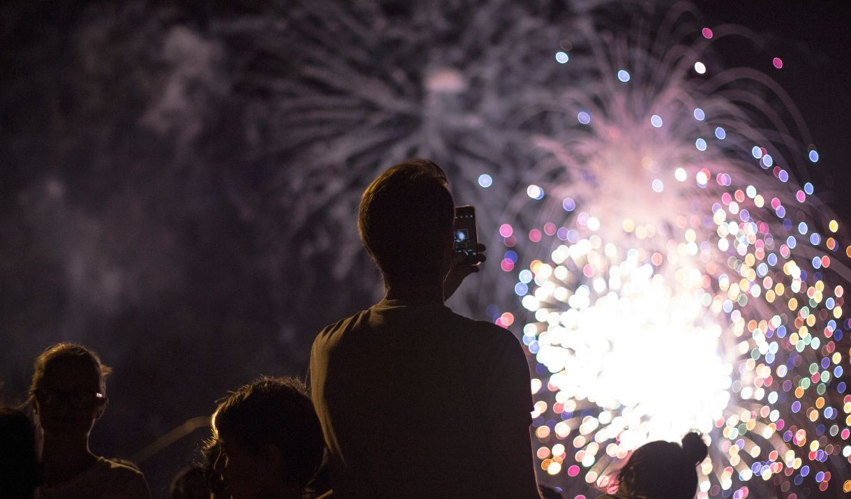 A person taking a photo of some fireworks