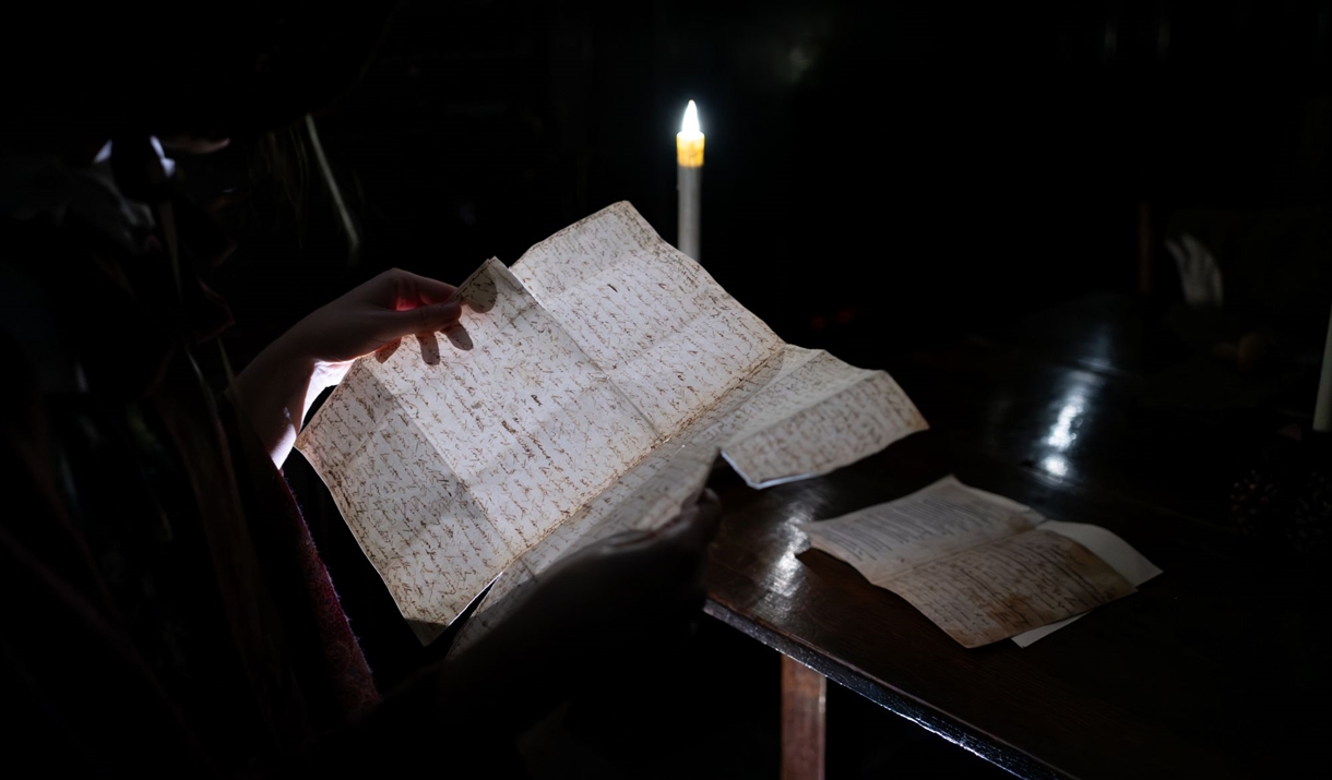 Spooky photograph of woman reading from handwritten letter