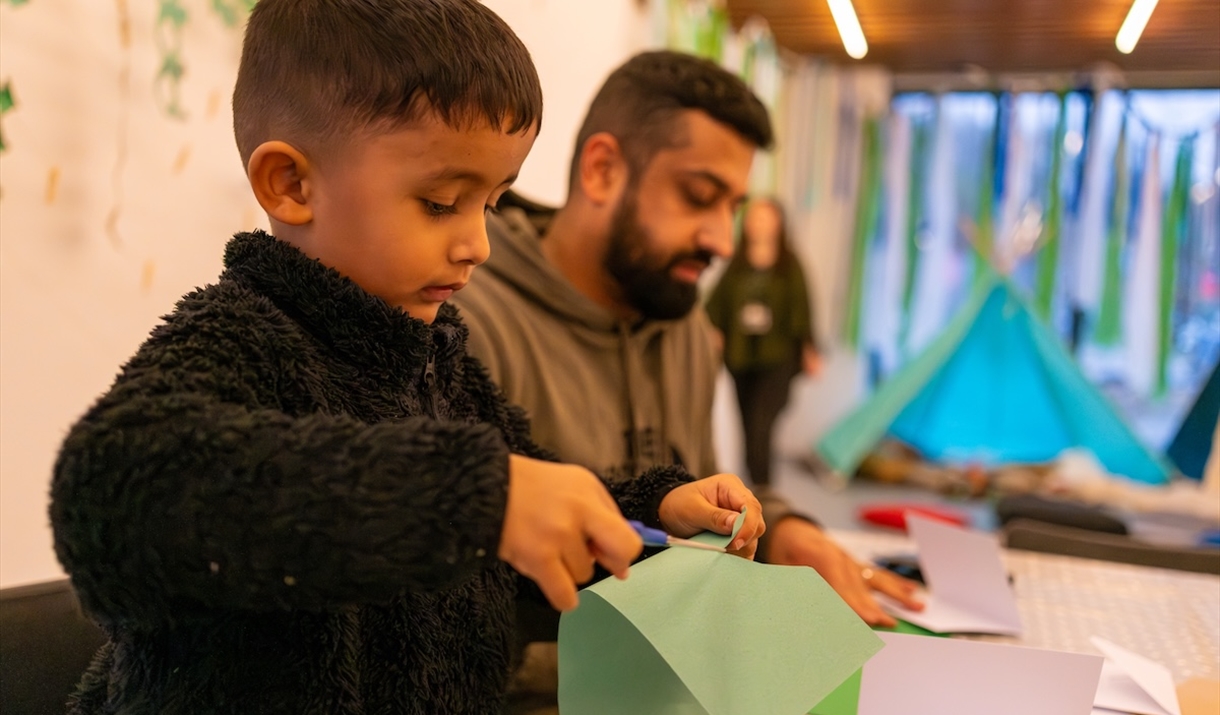 Child crafting in the learning centre with his dad