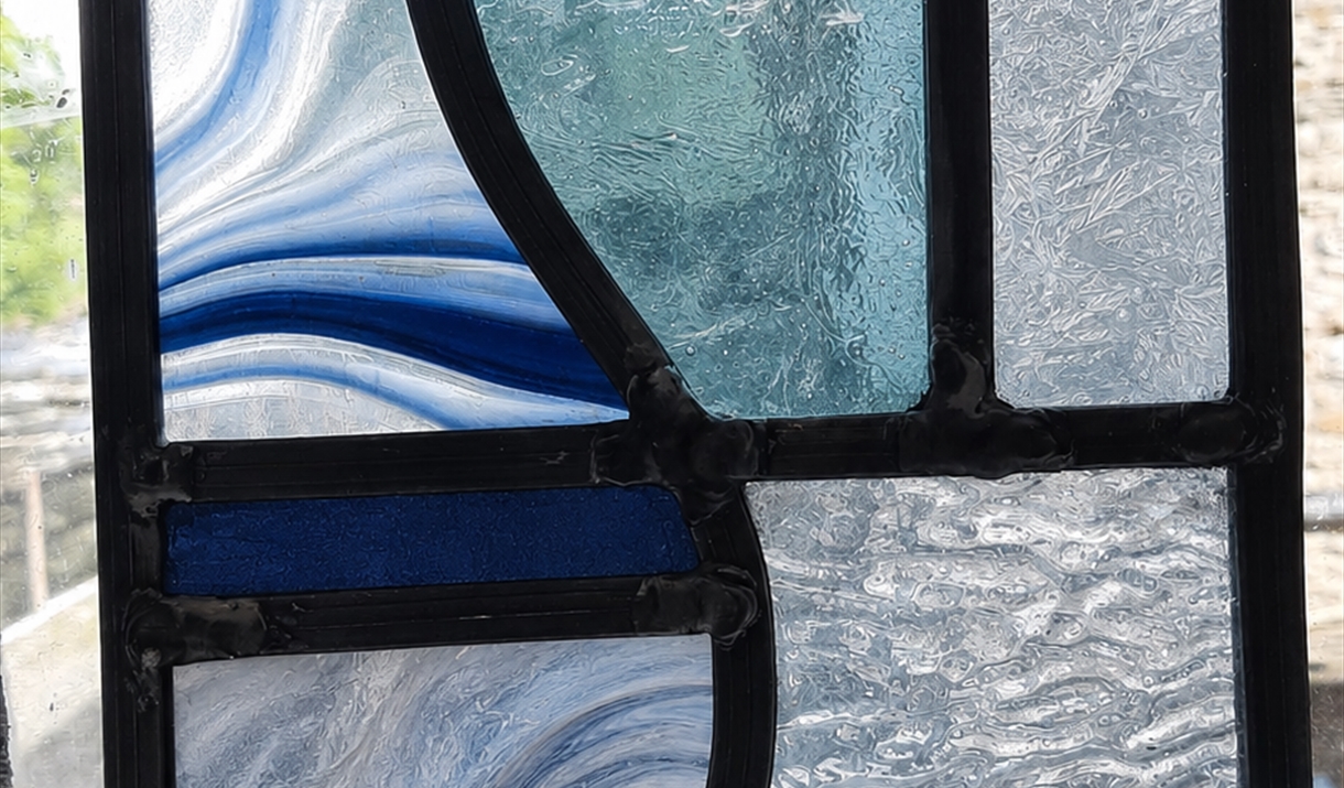 Stained glass window featuring intricate blue and white designs, showcasing artistic craftsmanship and vibrant colors.