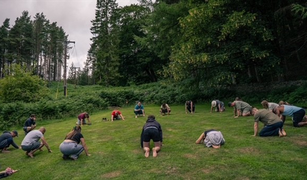 photo of people laying down in a circle in a field