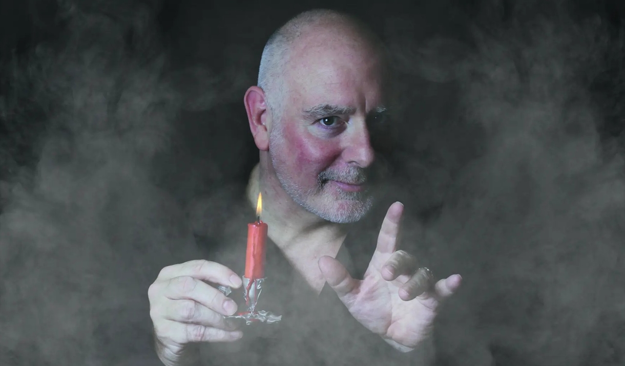 Photo of Scrooge holding a candle surrounded by mist